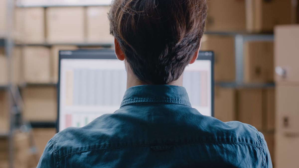 Person working at a computer with shelves in the background, symbolising control and organisation of SaaS subscriptions.